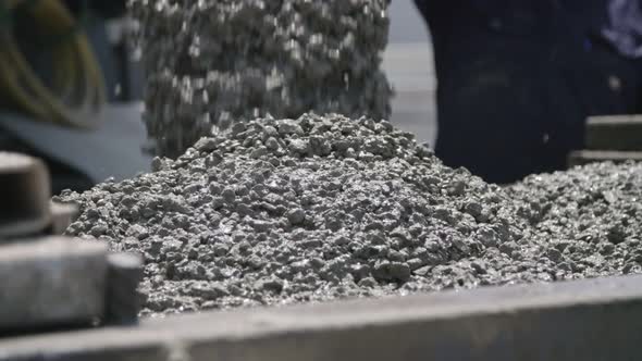 Workers pouring concrete into large steel molds on a construction site