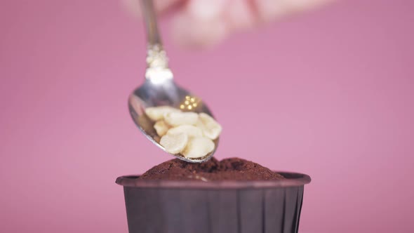 Closeup on a Rose Background in a Chocolate Cupcake with a Spoon Put the Nuts