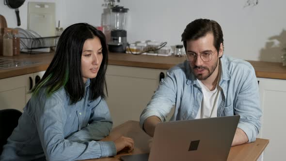 A young European Man Talking to an Asian female Colleague Working on an Online Project