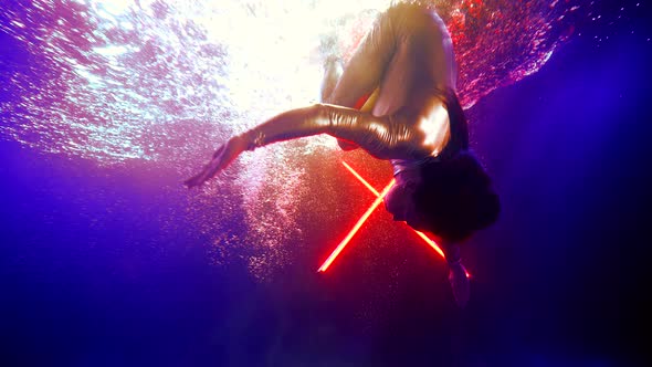 Woman in Cosmic Metallic Suit is Swimming Underwater Female Superhero is Doing Somersaults