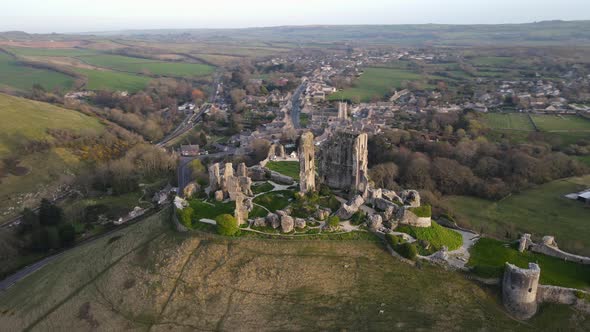 Hilltop Corfe Castle ruins in county Dorset at sunset, England. Aerial drone circling