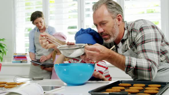 Father helping boy to filter flour using a strainer