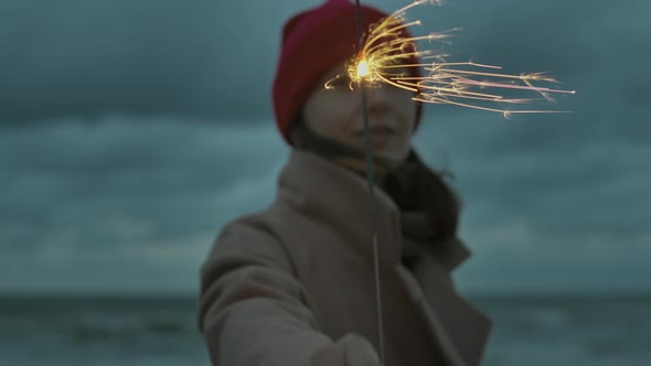 Woman with sparkle stick on the beach