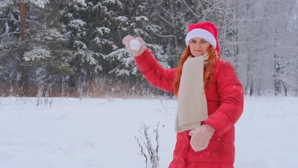 Winter 3A woman in a red Christmas hat throws snowballs