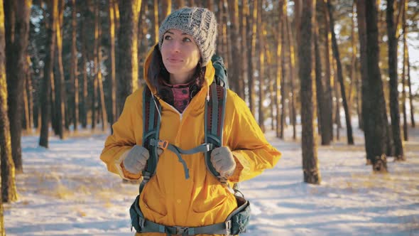 A Young Caucasian Girl with Backpack Going on Winter Forest Road in Snow Covered Winter Pine Forest