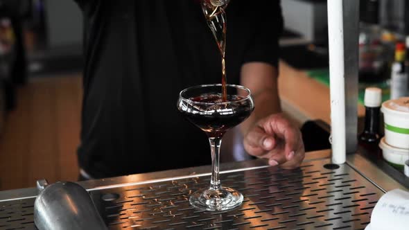 Black Manhattan being poured into a glass in slow motion. Rich brown tones are found in this shot fr