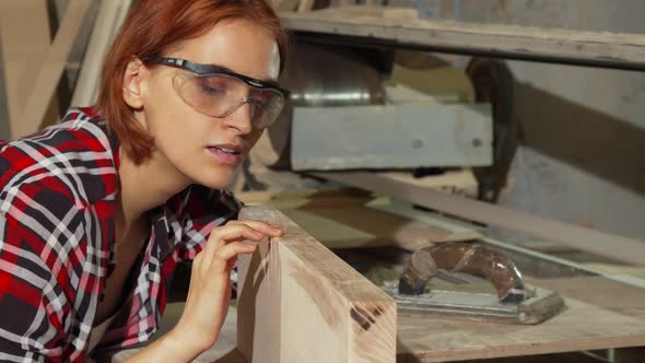 Female Carpenter Examining Wooden Plank After Sanding