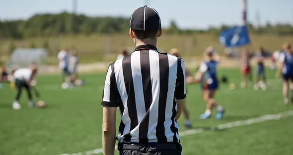 Female Sports Team Playing Rugby at the Stadium. Silhouette of the Referee Watching the Match. The