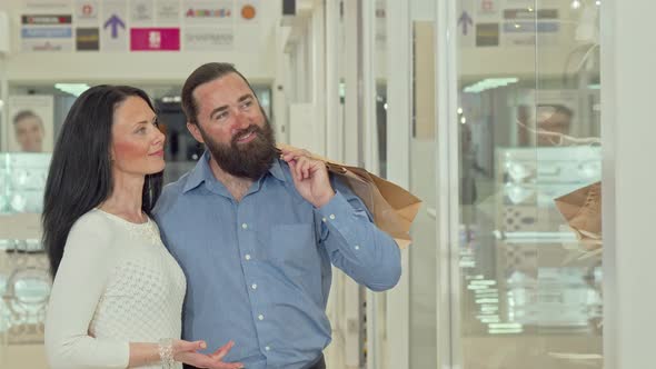 Happy Mature Couple Looking at Clothing Store Showcase at the Shopping Mall