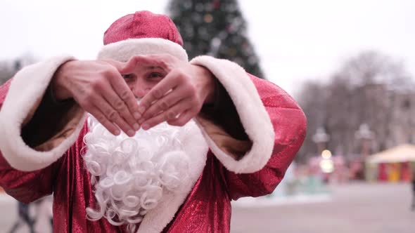 Santa Claus Shows a Heart Gesture of Kindness and Love Looking at the Camera