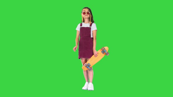 Casual Young Girl in Shades Holding a Skateboard Posing on a Green Screen Chroma Key