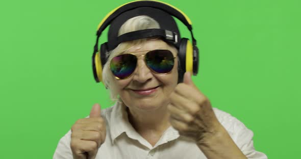 Elderly Woman Listens To Music in Headphones and Dances. Grandmother. Chroma Key