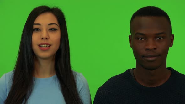 A Young Asian Woman and a Young Black Man Talk To the Camera - Closeup on the Faces - Green Screen