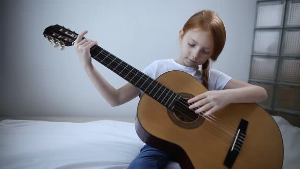 Red-haired Blogger Girl Plays Guitar on Camera. a Self-taught Girl Likes To Be Interesting for