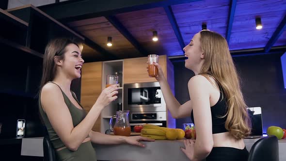 Young Women which Sitting Near the Kitchen Table and Drinking Fresh Juice