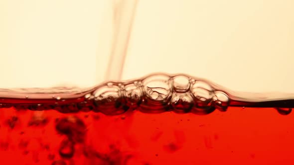 Red black tea pouring in glass teapot close up