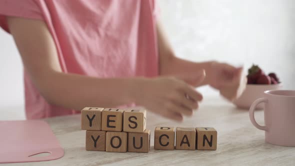 Motivating Quote Yes You Can On Table. Woman Makes A Joyful Positive Gesture With Her Hands