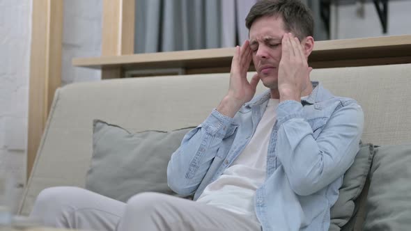 Stressed Young Man Having Headache in Living Room