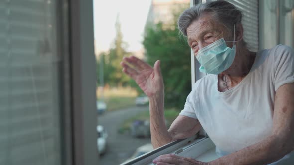 Happy Senior Woman in Mask Waves to Family From Window Hospital