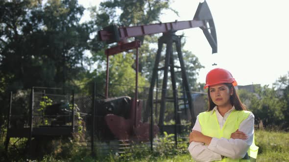 Portrait of Female Engineer Against Background of Oil Drilling Rig