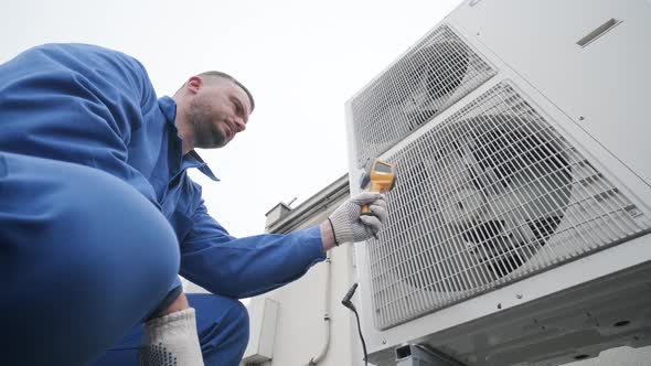 Technician uses a thermal imaging infrared thermometer to check the condensing