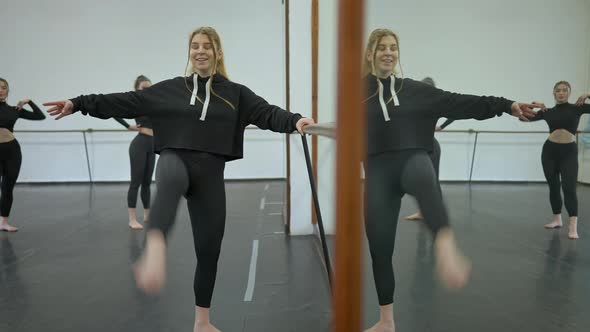 Smiling Confident Ballet Dancer Rehearsing Movement in Slow Motion with People Dancing at Background