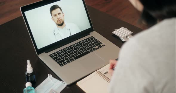 Back View of Woman Making Video Call with Her Doctor While Staying at Home During Coronavirus