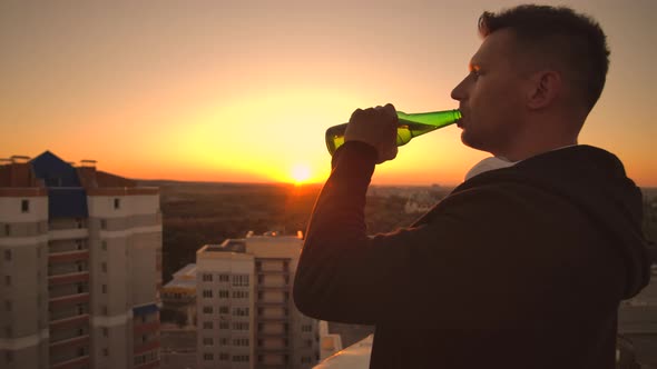 A Man Drinks Beer Standing on the Roof and Contemplates the World. Look at the View of the City at