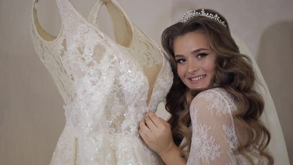 Beautiful and Lovely Bride in Night Gown and Veil Standing Near Wedding Dress