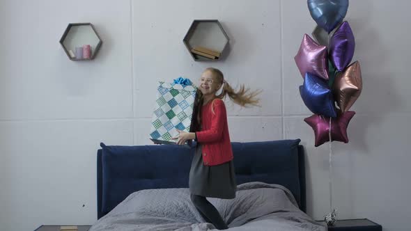 Birthday Teen Girl Jumping on Bed Holding Gift Box
