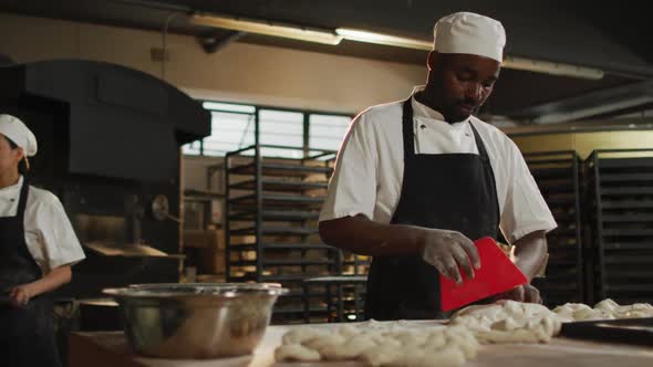 Animation of happy african american male baker cutting sourdough for bread