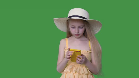 Young Girl in Hat and Yellow Dress Using Mobile Phone on Transparent Green Background