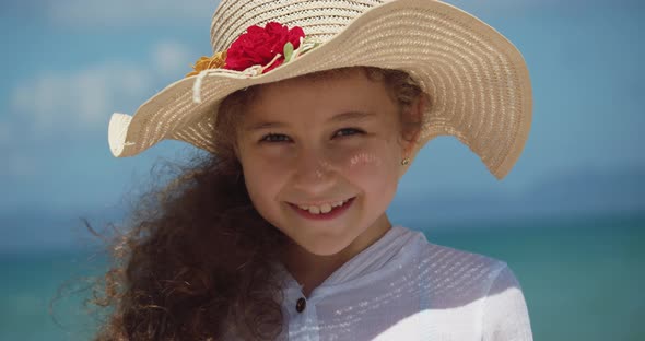 Portrait of a Funny Little Girl in a Hat a Smiling Child Looking at the Camera Stands on the Beach