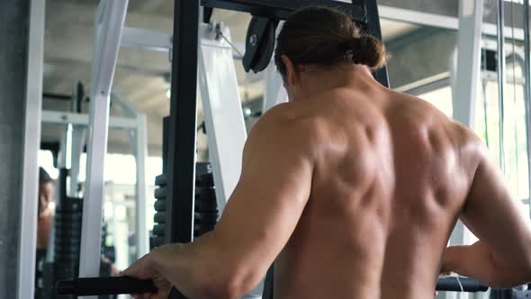 Shirtless Muscular Man Doing Seated Cable Row Exercise on Machine at the Gym