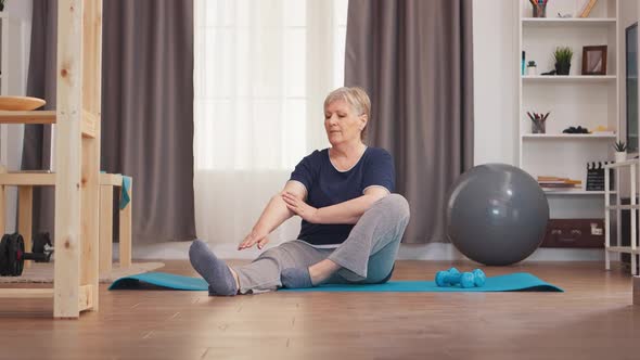 Old Woman Stretching on Yoga Mat