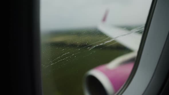 View Through Rainy Window of Airplane Successfully Landing Runway at Airport