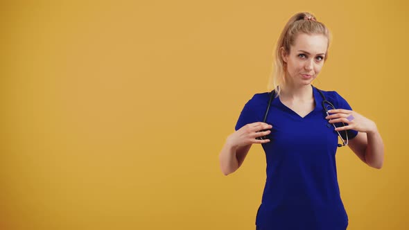 Young Caucasian Blonde Female Doctor in Blue Uniform with Stethoscope Over Her Neck Looking at