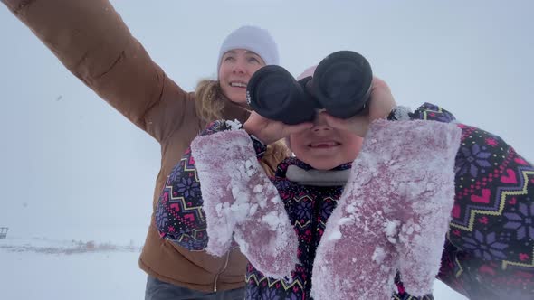 Mother and Little Girl Using Binoculars Winter.Having Fun Together at Wintertime