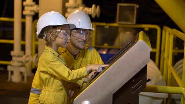 A Young Man and a Little Boy Are Both in a Yellow Work Uniform, Glasses, and Helmet in an Industrial