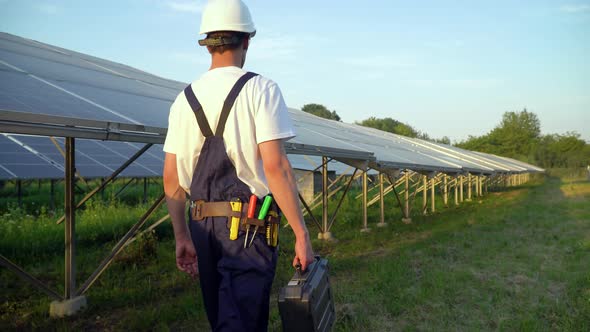 Technician Walking in Solar Cell Farm Through Field of Solar Panels Checking the Panels at Solar