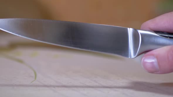 A Woman Hand is Holding a Sharp Long Kitchen Knife Over Surface of Table