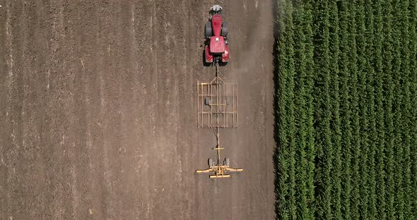 Red tractor flattening a field for seeding, Drone follow footage.