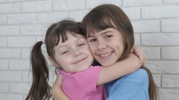 Happy little sisters hugging.