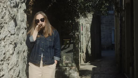 Brunette woman  in sunglasses uses her phone in the city.