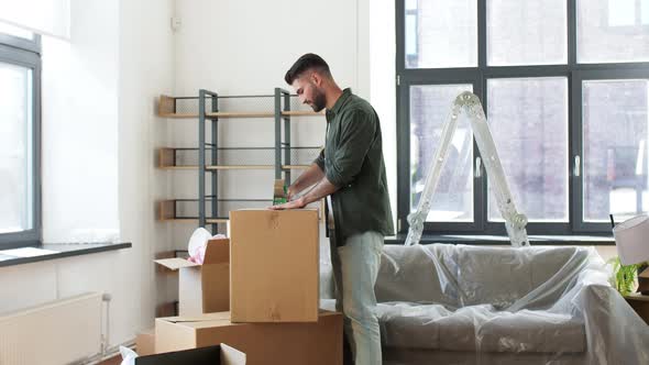 Man with Adhesive Tape Packing Box at Home