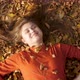 Happy beautiful young woman ying in autumn foliage in park enjoying life - VideoHive Item for Sale