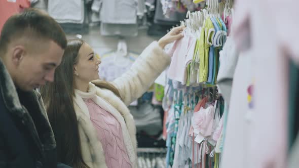 Couple Stands in Baby Clothing Section and Chooses Tshirt