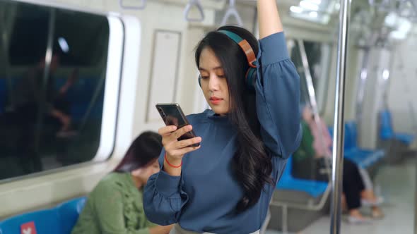 Young Woman Using Mobile Phone on Public Train