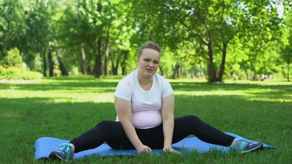 Obese Girl Clumsy Doing Fat-Burning Exercises Outdoors, Tired, Disappointed