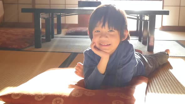 Cute Asian Child Lying In Living Room Under Sunlight From Window On Winter Day